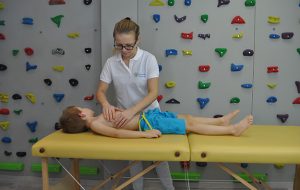 Masaż leczniczy dziecka leżącego na stole rehabilitacyjnym